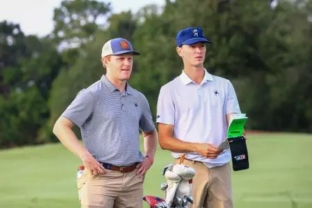 Zwei Golfer beraten sich auf dem Platz mit einem Yardage-Buch