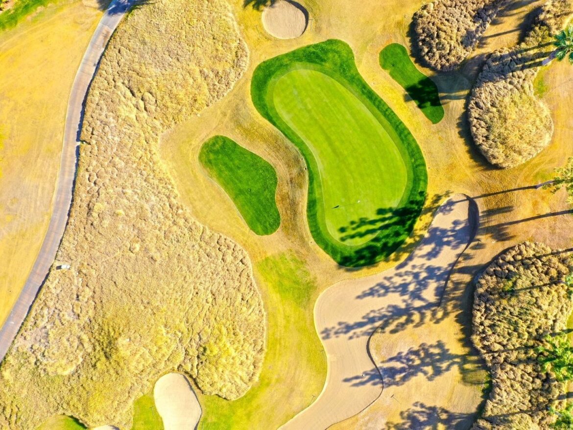 Draufsicht auf ein gepflegtes Golfloch mit Grün, Bunkern und Fairway
