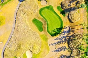 Draufsicht auf ein gepflegtes Golfloch mit Grün, Bunkern und Fairway