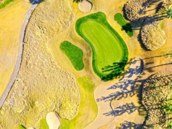 Draufsicht auf ein gepflegtes Golfloch mit Grün, Bunkern und Fairway