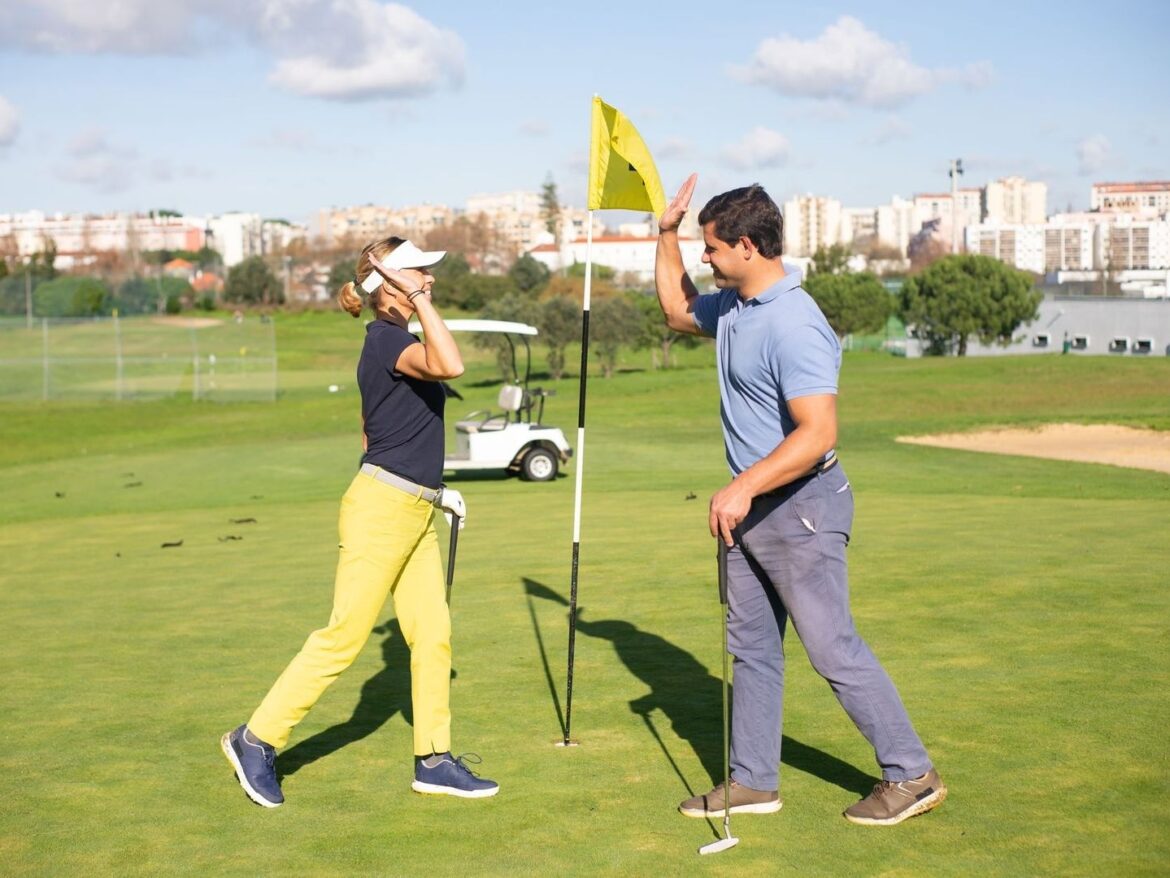 Zwei Golfer begrüßen sich mit erhobenen Händen auf dem Grün