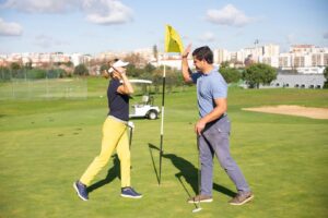 Zwei Golfer begrüßen sich mit erhobenen Händen auf dem Grün