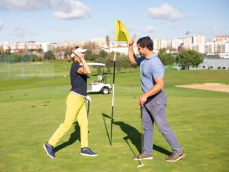 Zwei Golfer begrüßen sich mit erhobenen Händen auf dem Grün